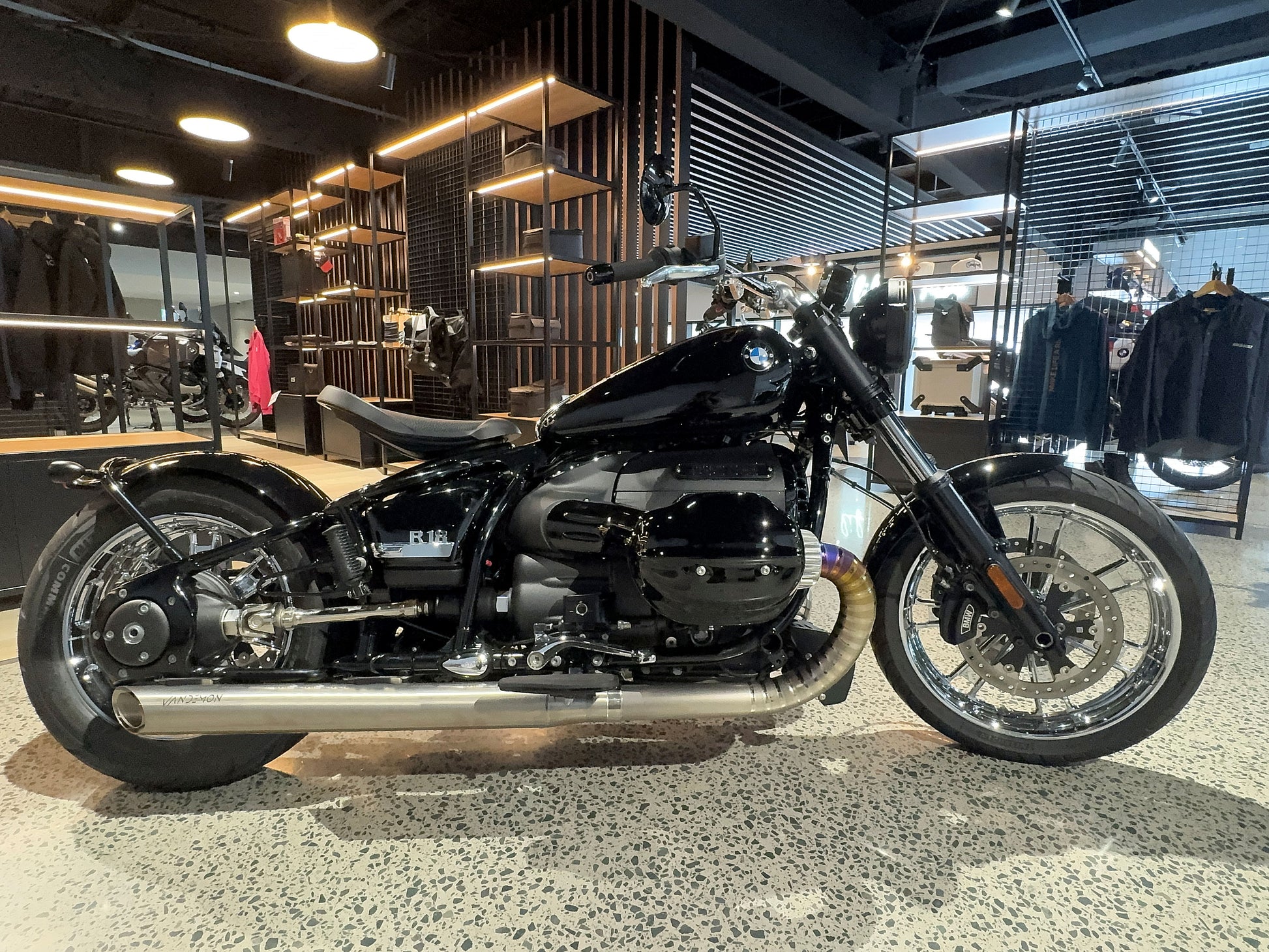 A motorcycle stands parked in a retail store, surrounded by various products on display.