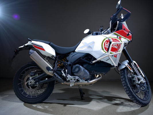 A white Ducati Rally motorcycle,off road tires,parked in a garage.