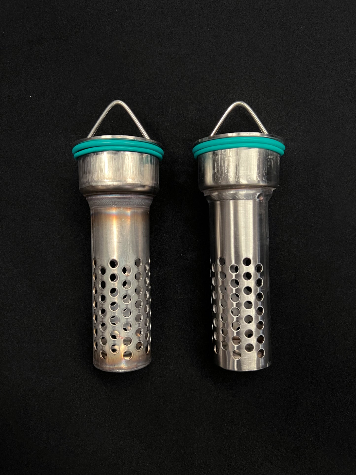 Two metallic cylindrical objects with perforated designs on a black background