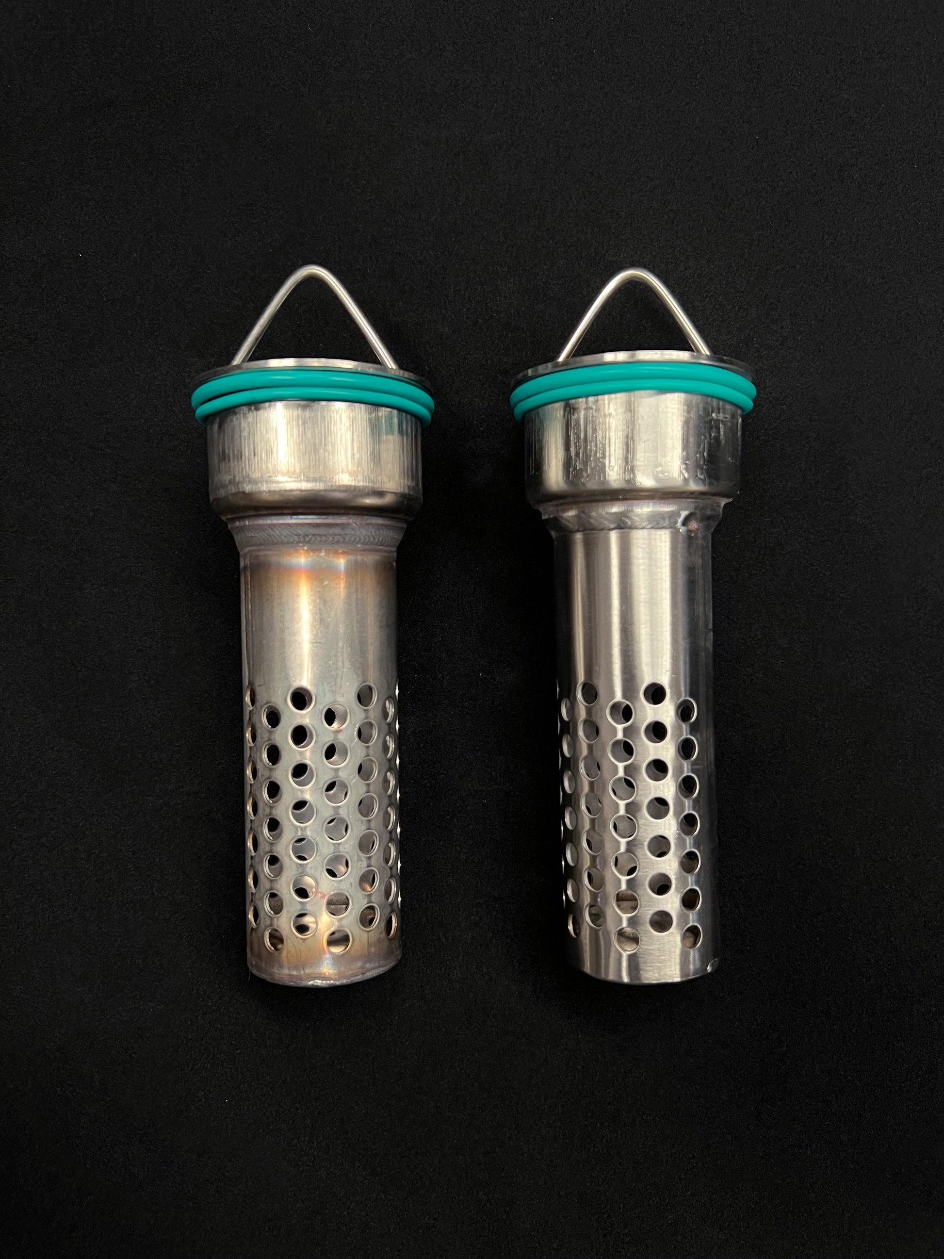 Two metallic cylindrical objects with perforated designs on a black background
