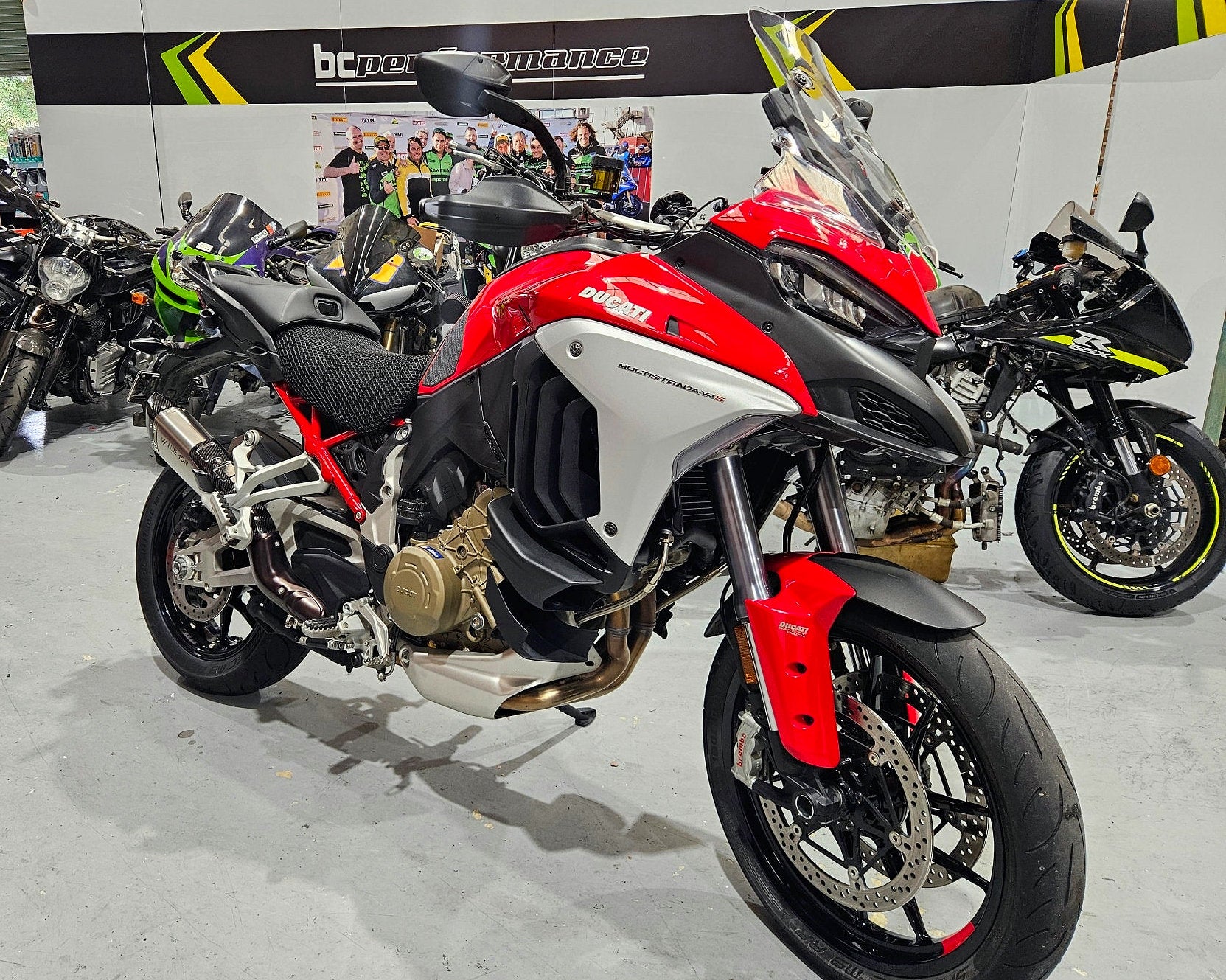 Red and black motorcycle on display in a showroom with other motorcycles.