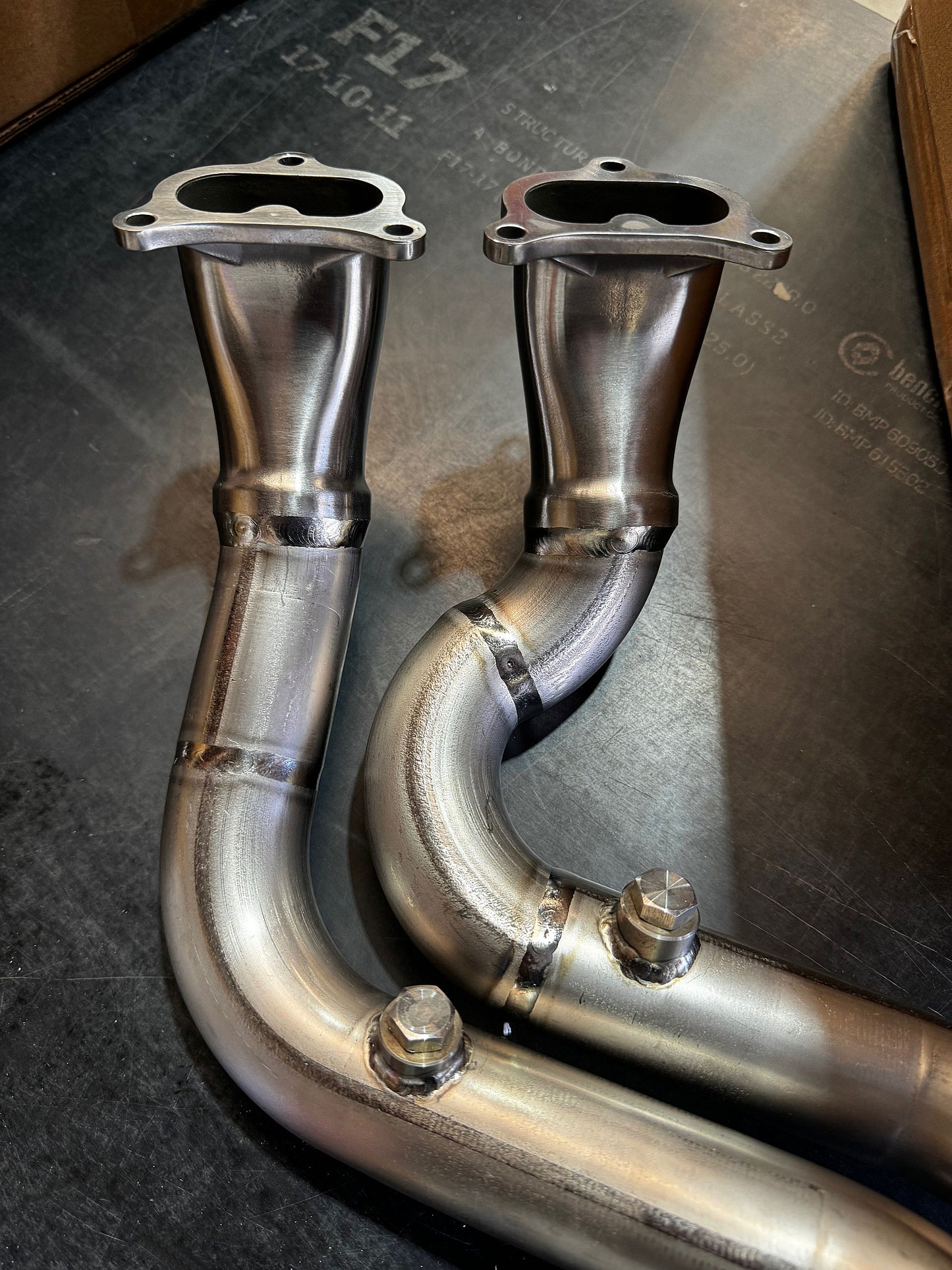 Two metallic exhaust pipes on a dark surface