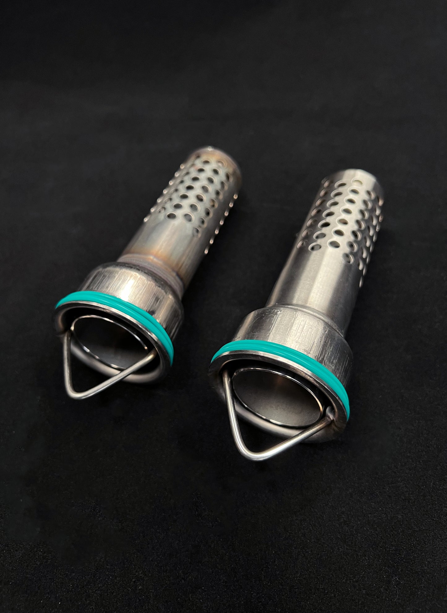 Two metal grinders with teal accents on a black background