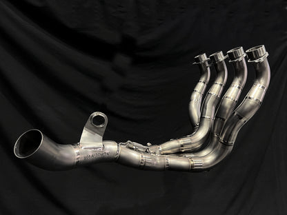 Polished 4-into-1 motorcycle exhaust header with precision welds and flanges, laid out with collector pipe.