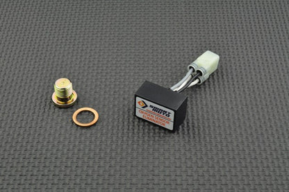 Mechanical components, including a bolt, washer, and electronic module, on a textured grey surface.