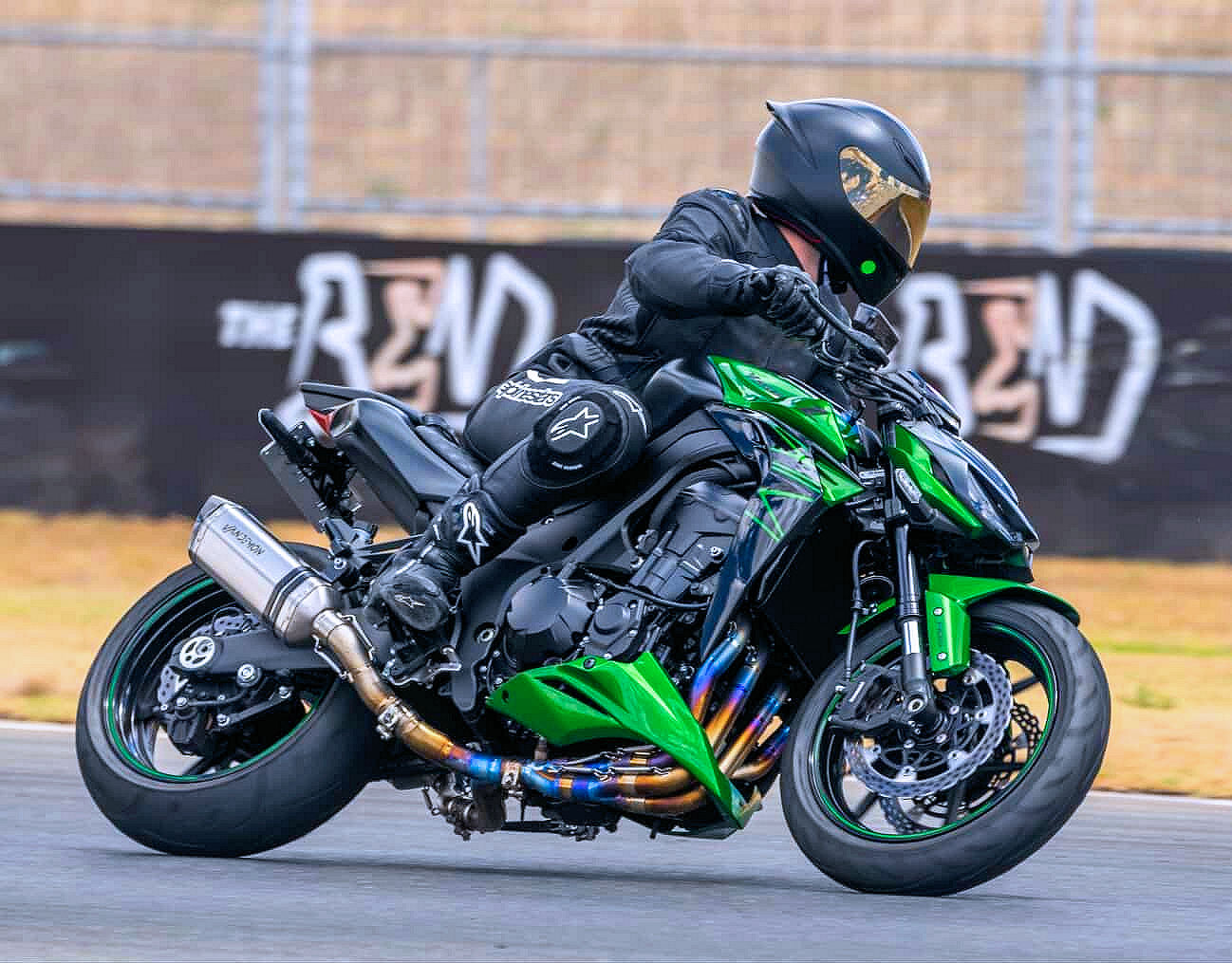 Person riding a green and black motorcycle on a track.