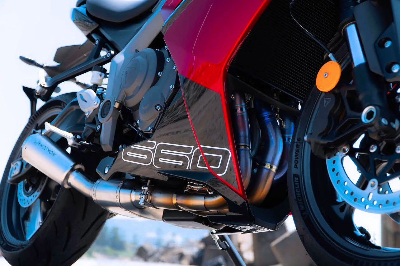 Close-up of red motorcycle's exhaust, back tire, engine.