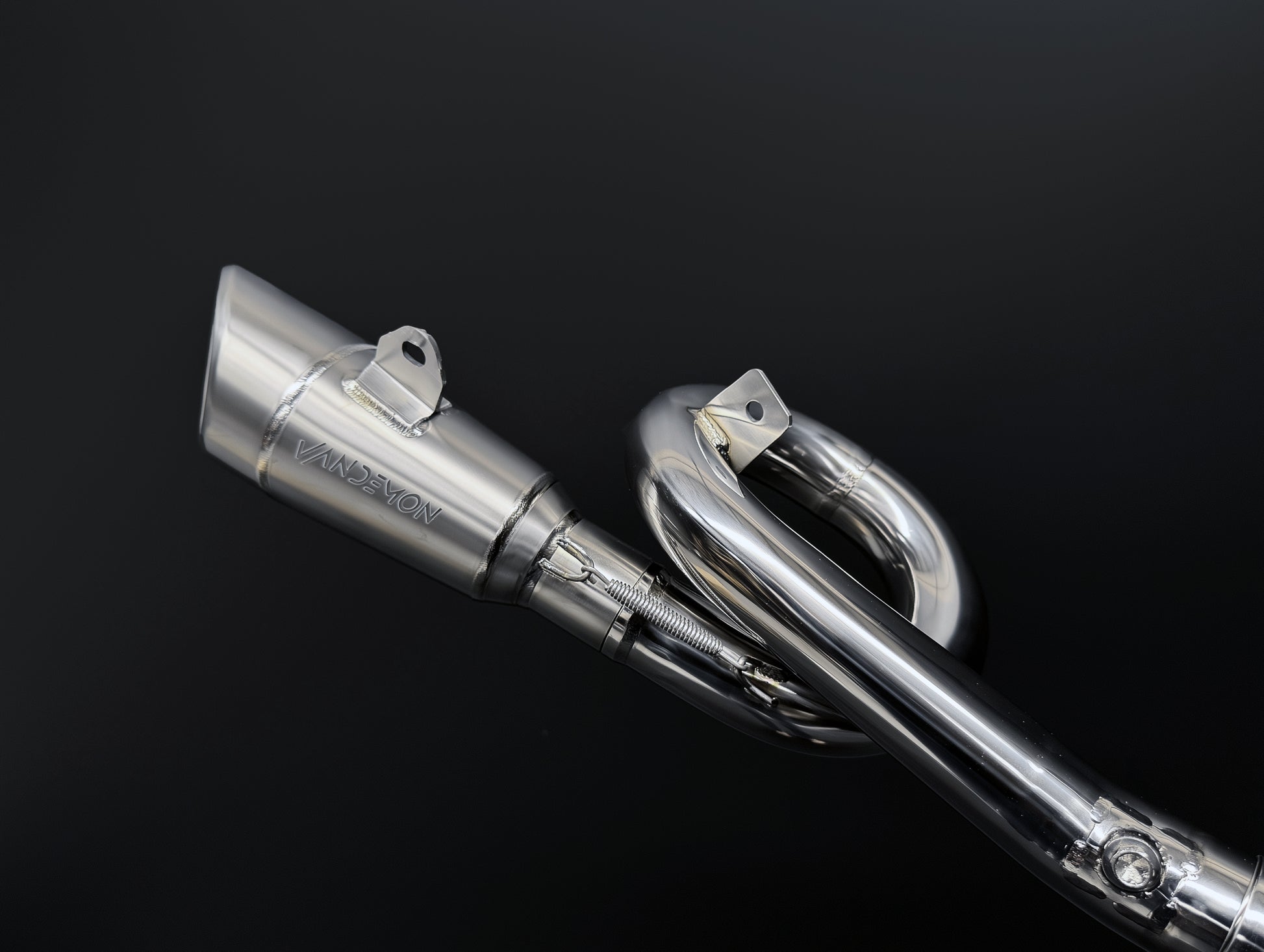 Close-up of a Vandemon motorcycle exhaust system on a black background