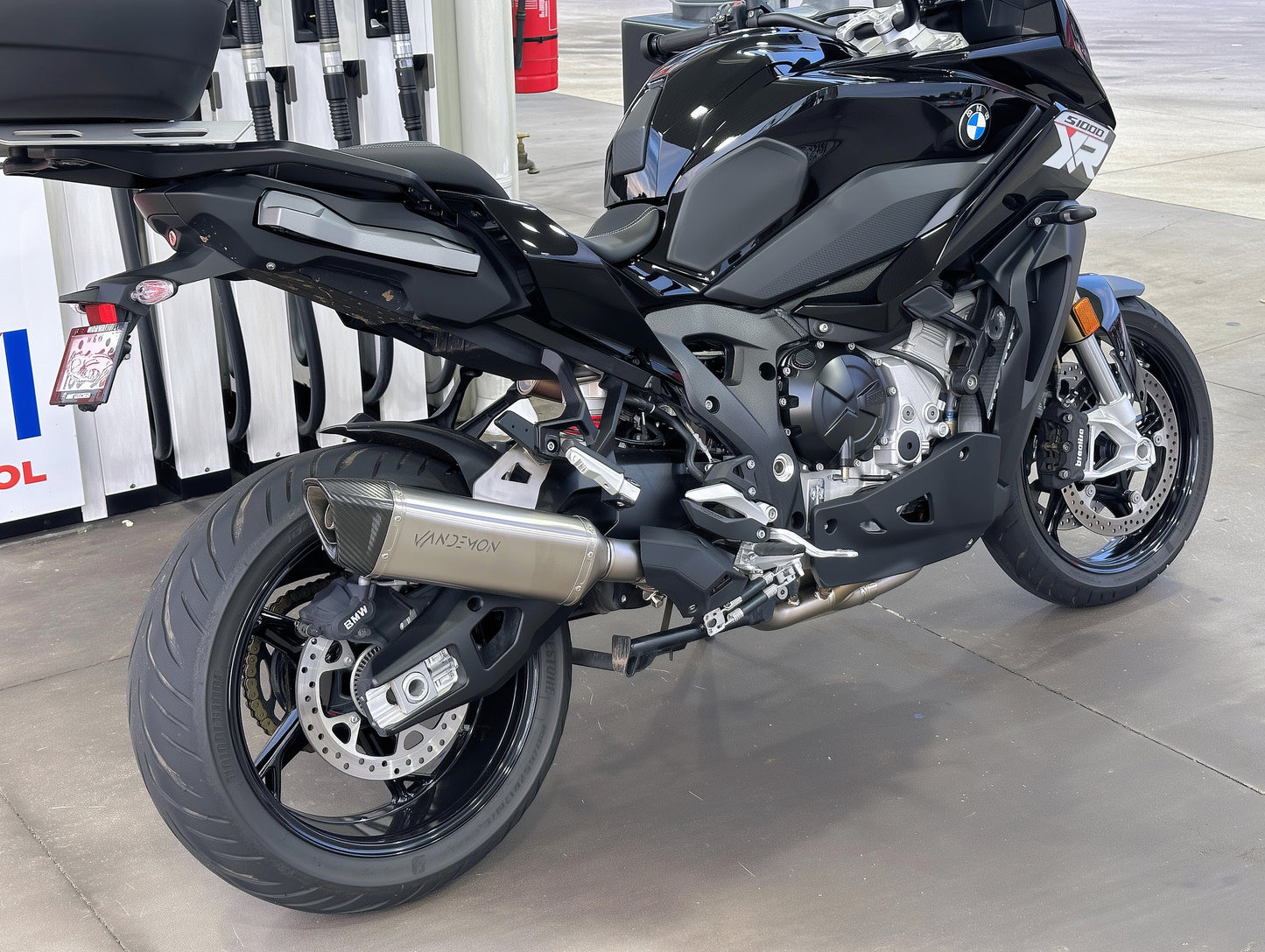 Black BMW motorcycle on a showroom floor with Vandemon exhaust